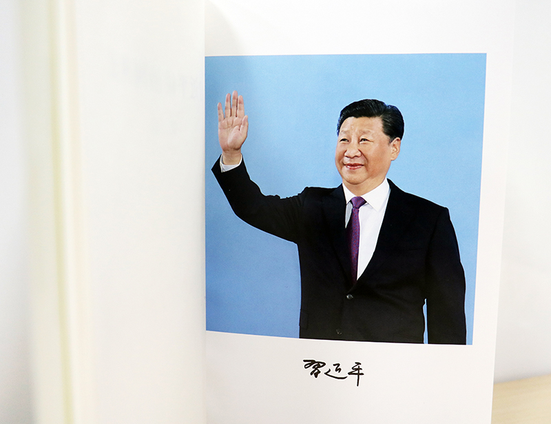 说明: 图为《习近平谈治国理政》第二卷扉页后习近平总书记挥手照片，下有总书记个人签名。